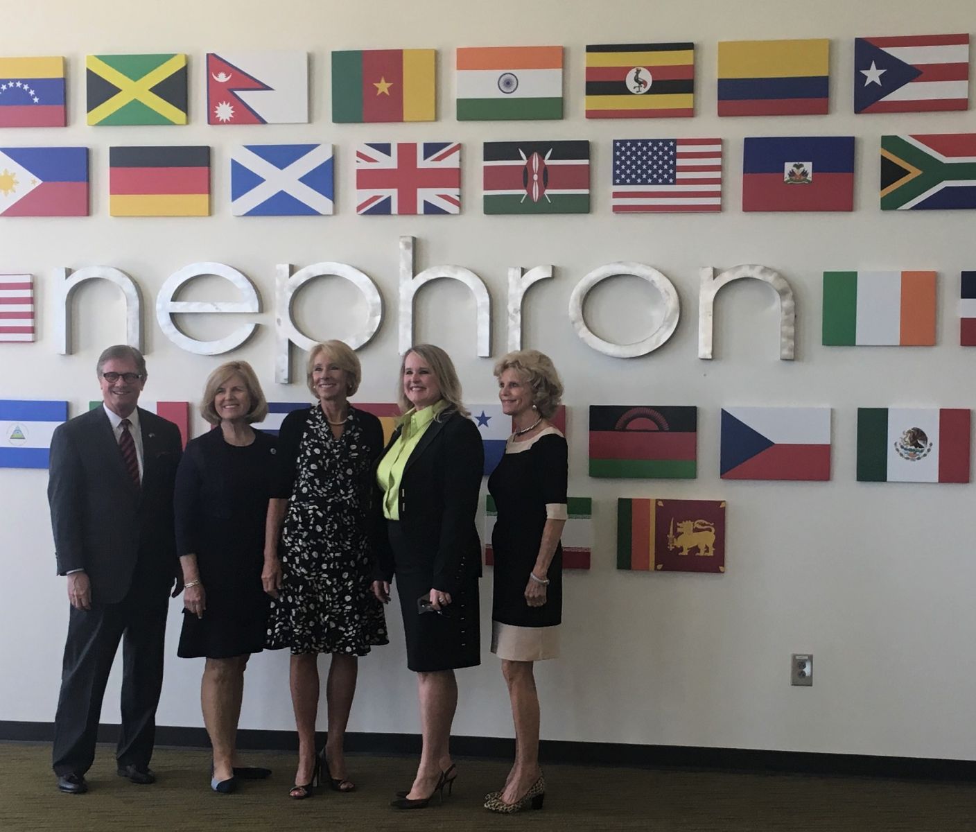 Officials including S.C. Superintendent of Education Molly Spearman (second from left), U.S. Secretary of Education Betsy DeVos, Nephron CEO Lou Kennedy and S.C. first lady Peggy McMaster toured Nephron's West Columbia facility on Thursday. The group posed in front of a lobby display featuring the flags of countries of origin of Nephron employees. (Photo/Renee Sexton)