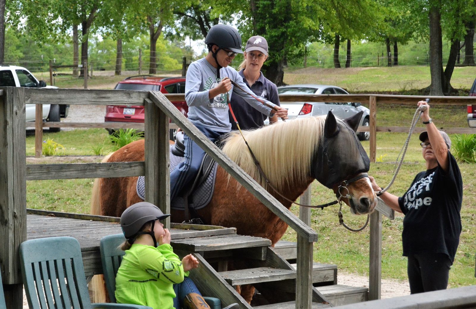 Jennifer Stoudemire, executive director and head instructor at Dream Riders in Lexington, helps Mateo Aranda get on his horse to begin a lesson. Leading Mateo is volunteer Rosie Brooks. (Photo/Travis Boland)