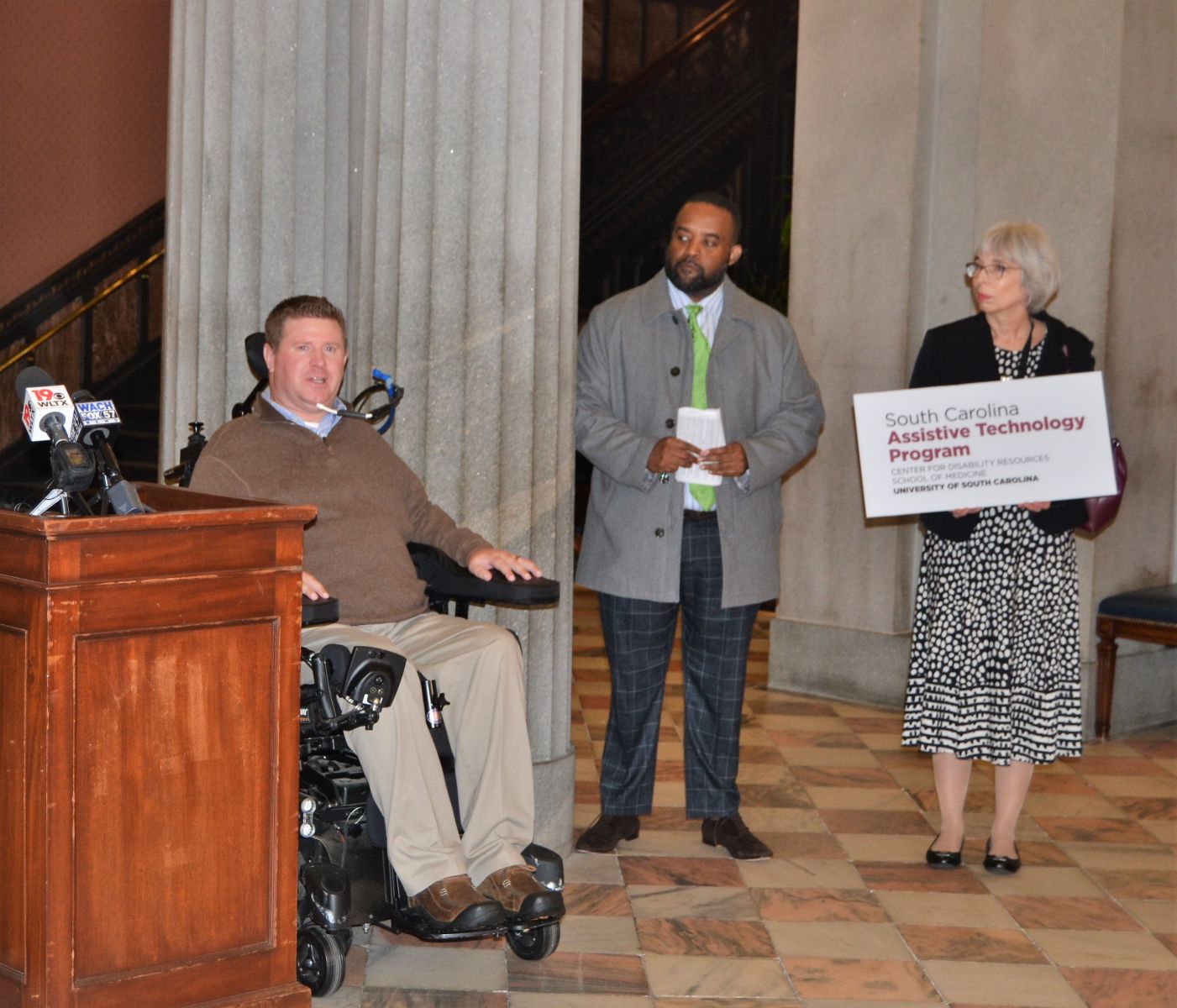 Brian Denny (left), outreach coordinator at the S.C. Spinal Cord Injury Association, speaks during a Feb. 26 ceremony at the Statehouse designating March as Assistive Technology Awareness Month. (Photo/Melinda Waldrop) 